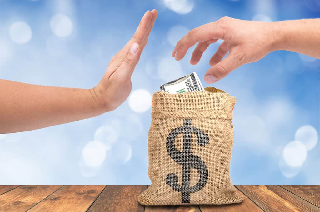 A hand refusing cash beside a money bag, on the tyranny of the lowest bid in rehab and maintenance